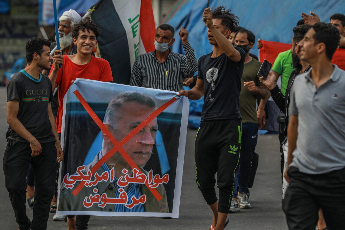 Protestors in Baghdad hold a defaced picture of Mustafa Al-Kadhimi during an April, 2020 demonstration