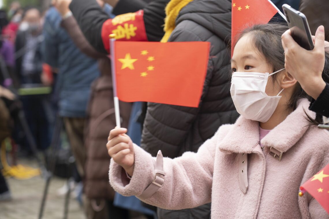 A masked girl waves a Chinese flag