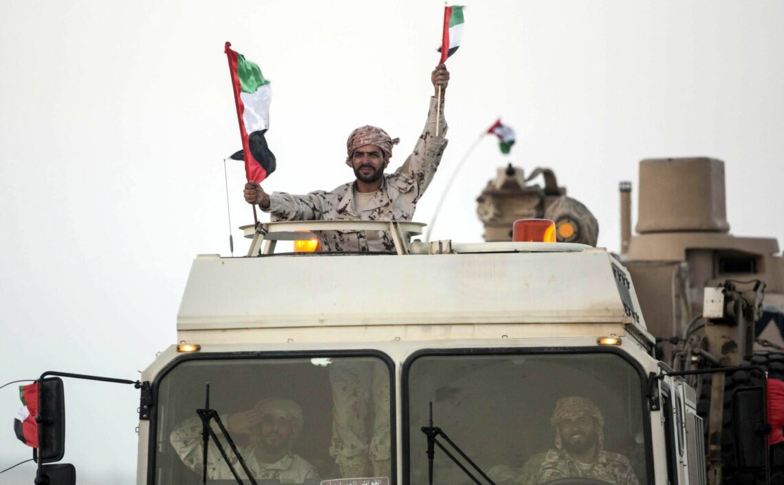 An Emirati soldier waves flags from a military vehicle Yemen conflict
