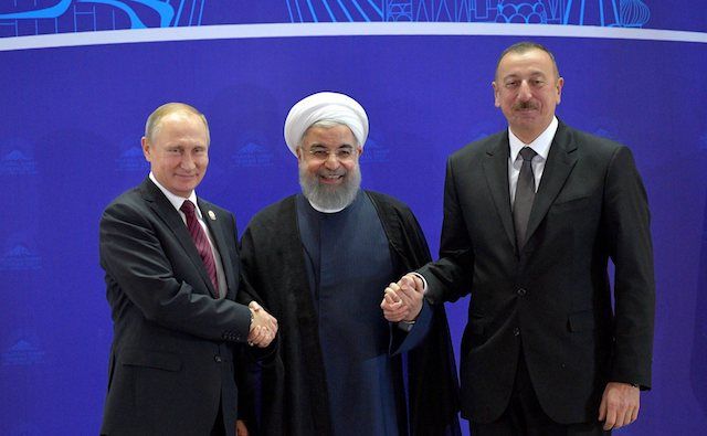A photo of the leaders of Russia, Iran and Azerbaijan holding hands at a summit in Tehran before formal talks