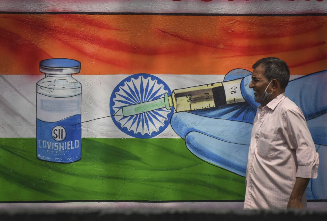 A man in India walks past vaccine promotional artwork
