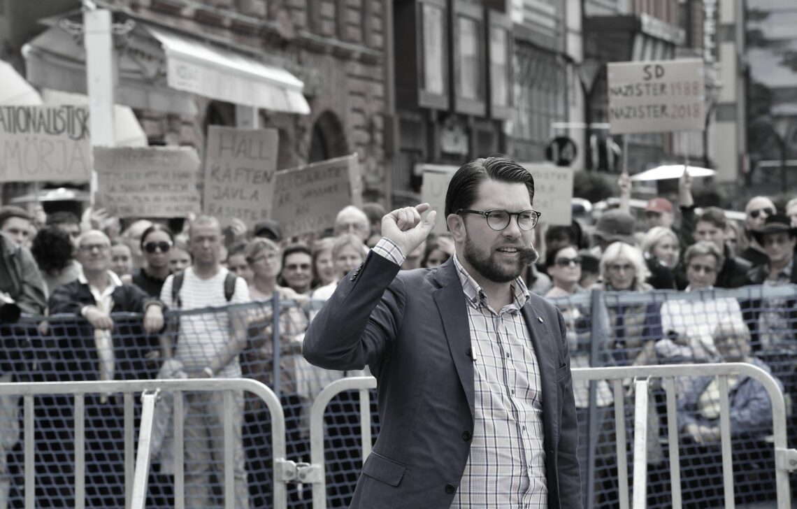 Sweden Democrat party leader Jimmie Akesson speaks at an election rally with protestors gathered behind him