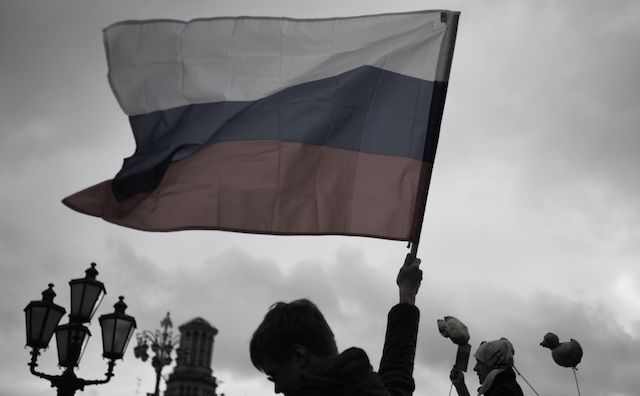 A picture of a man hoisting the flag of the Russian Federation