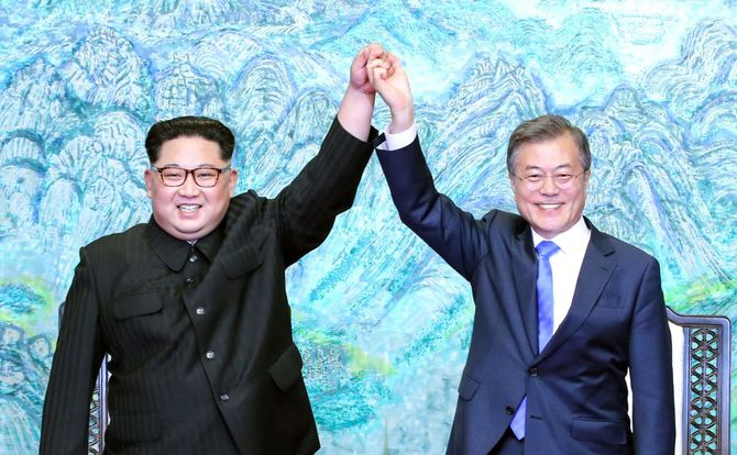 North Korean leader Kim Jong-un and South Korean President Moon Jae-in hold hands in the air triumphantly during an April 27, 2018 meeting