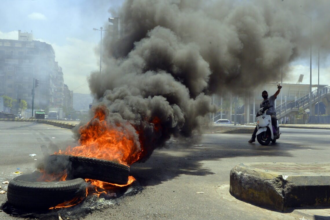 A protester poses near burning tires in Beirut Lebanon crisis