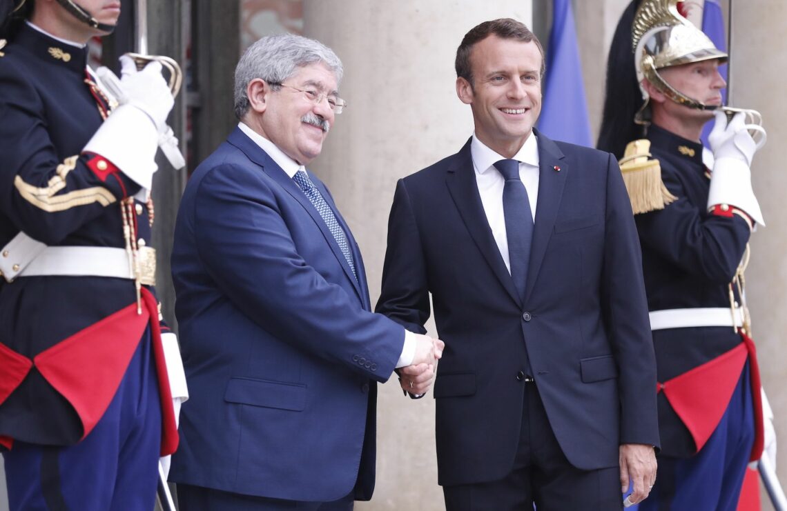 The Algerian prime minister and French president shake hands at a May 2018 meeting