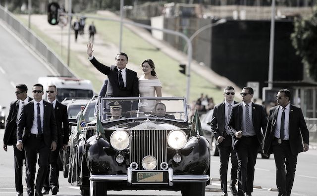 A photo of Brazil’s president and his wife riding in a stylish open limousine surrounded by secret service officers for his swearing-in ceremony