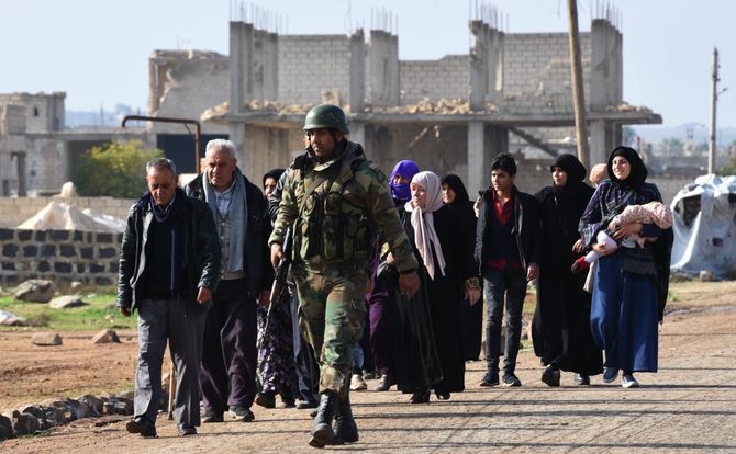 Syrian government troops escort residents of Idlib Province through a control point