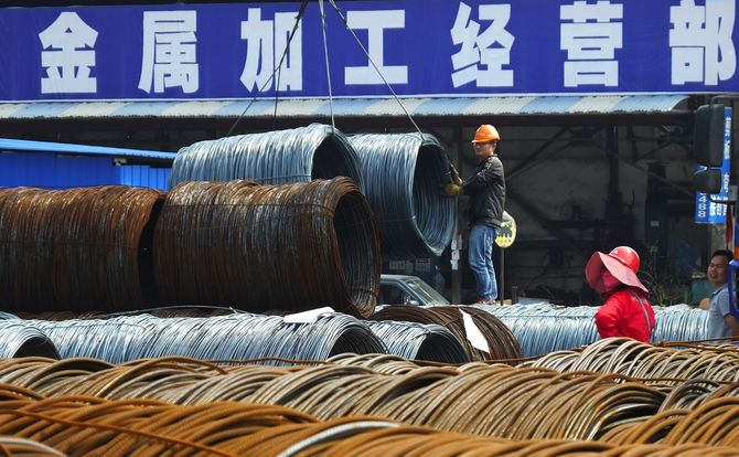 Chinese steelworker directs crane to pick up coils of wire in Yichang city, Hubei province cut spending drastically