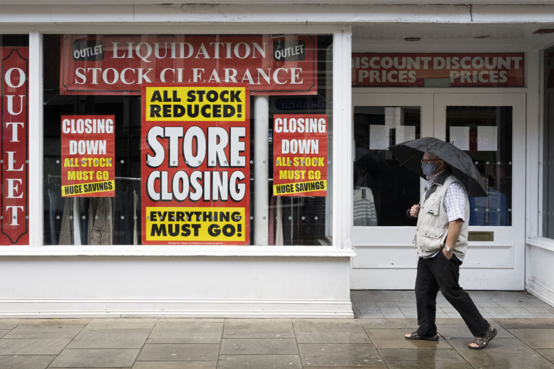 A man walks past a closing store during a lockdown in Wales, October 2020