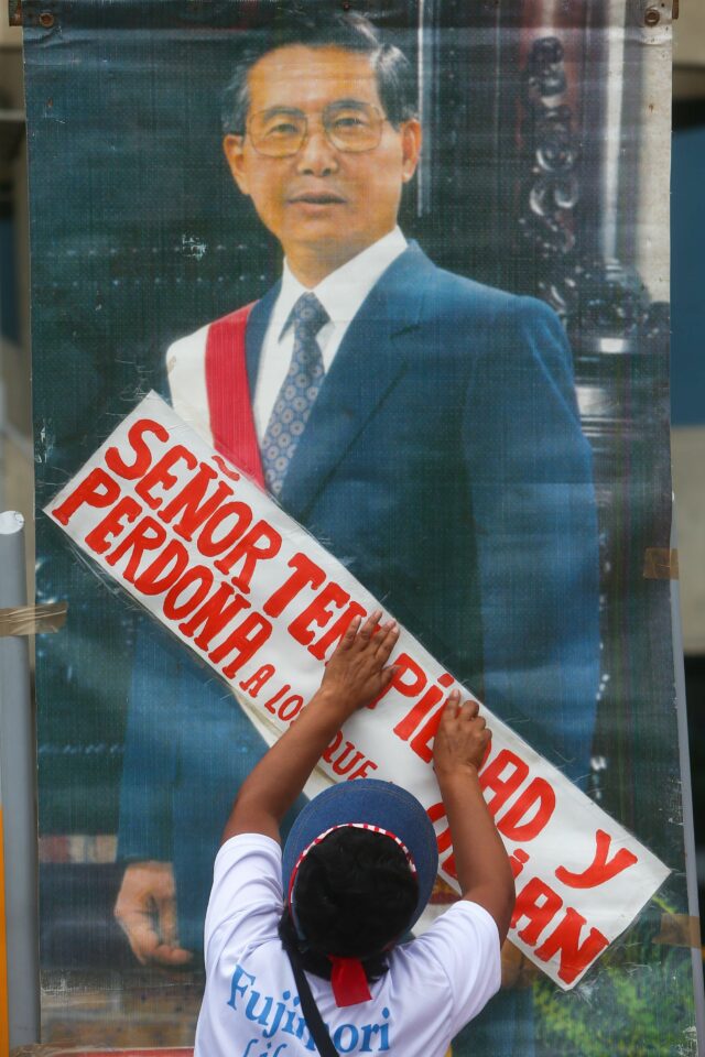 A Fujimori supporter puts up a sign on a picture of the former president