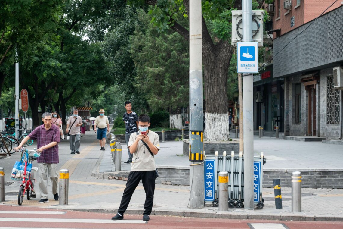 Man standing at a road crossing looking at his phone in China