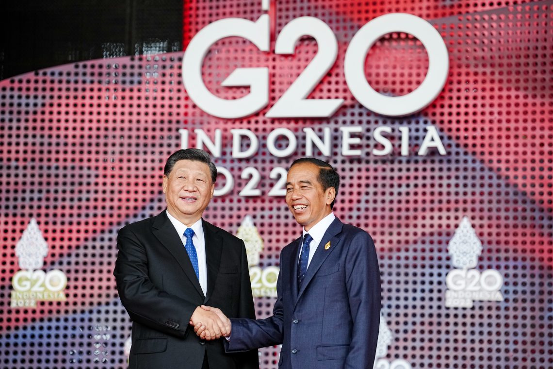 Two men shaking hands in front of a sign