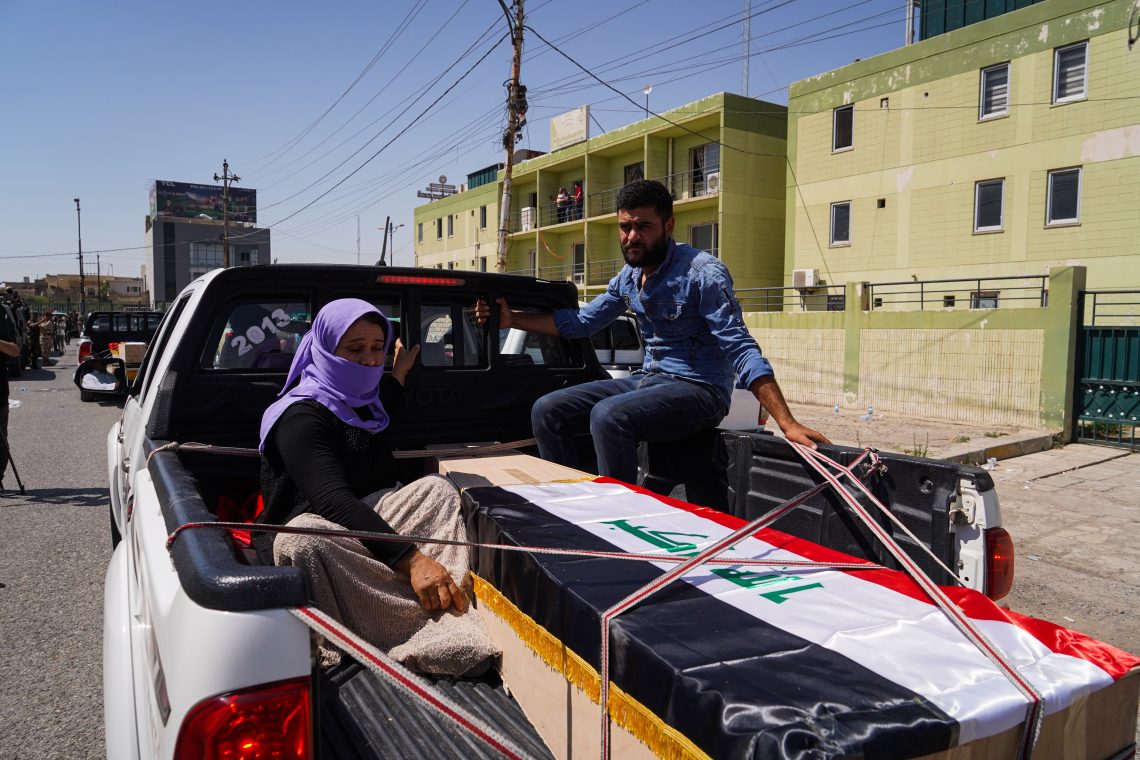 A man and a woman in the back of a pickup truck with a coffin