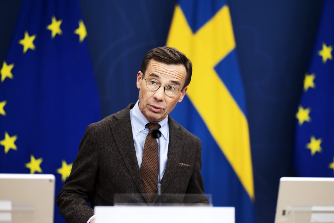 Man in a suit and tie in front of flags