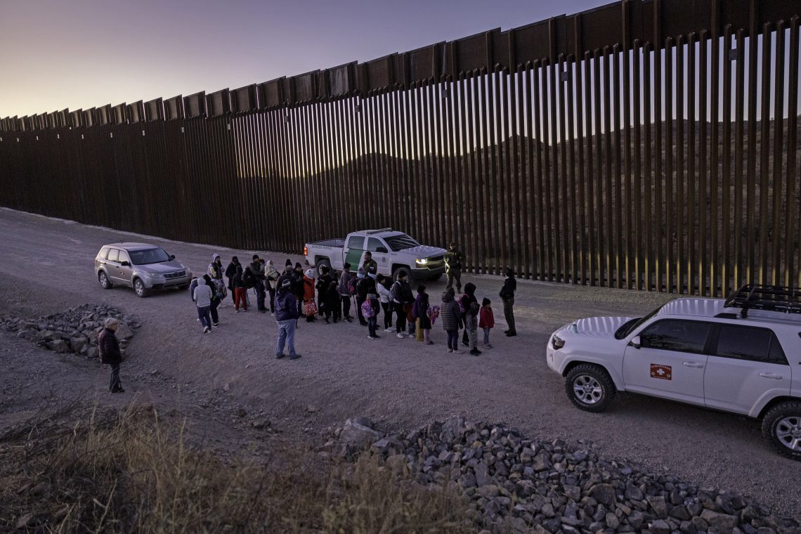 Jan. 19, 2025: U.S. Border Patrol agents prepare to transport immigrants for processing next to the U.S.-Mexico border fence in Arizona. Although migrant crossings have significantly declined over the past year, the new Trump administration has promised to completely “seal off” the border.