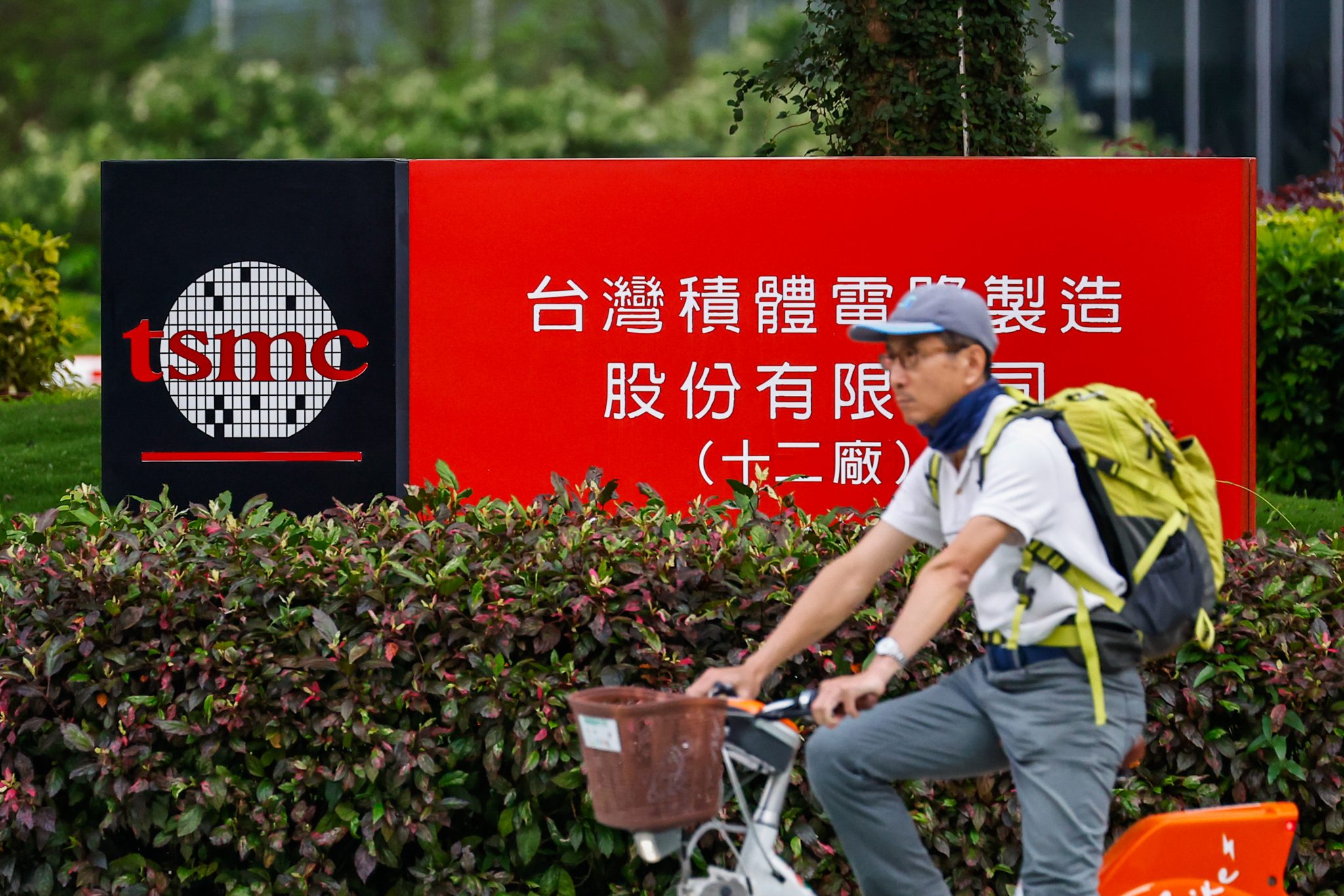 台灣單車手在台積電廣告牌前等紅綠燈。台灣生產全球約九成先進電腦晶片。