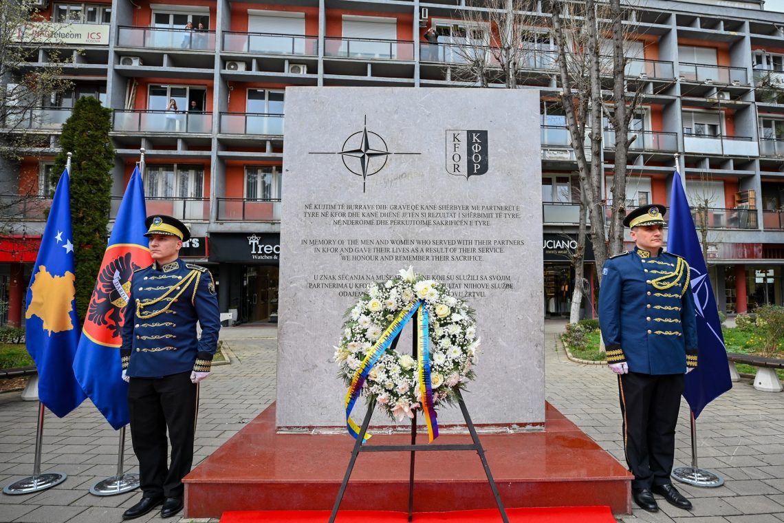 Two soldiers stand at a monument commemorating the UN's peacekeeping mission in Kosovo.